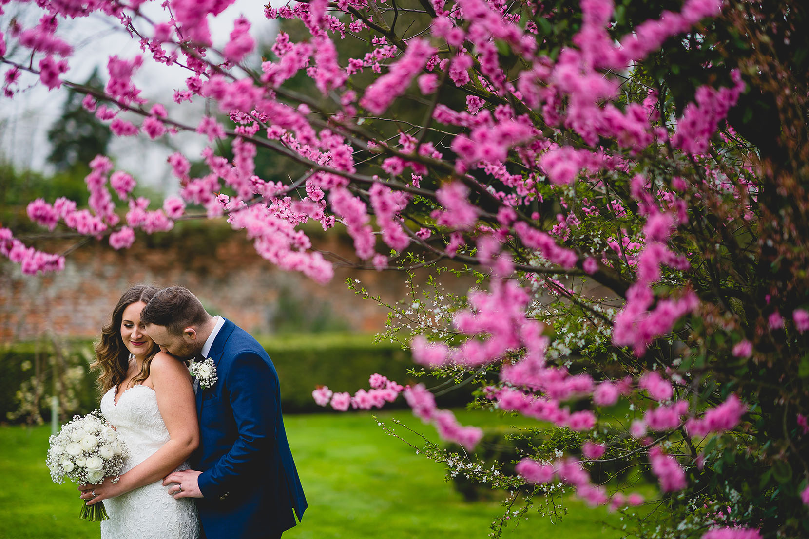 Laura and Grant having a snuggle in the blossum at Southwood Hall for their April Wedding