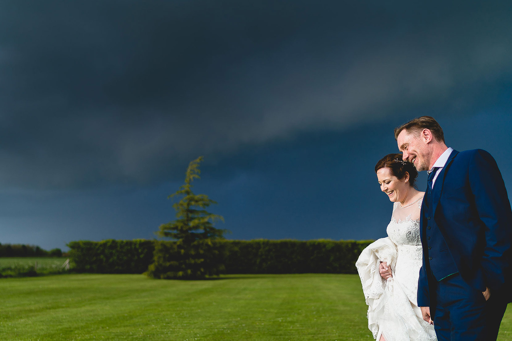 carl and paul walking out to get some bridal portaits on their wedding day at elms barn with a very stormy sky